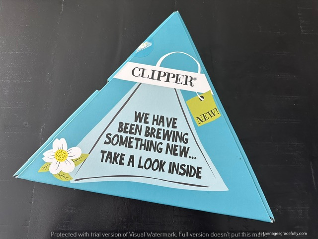 Een driehoekige verpakking van Clipper met de tekst 'We hebben iets nieuws gebrouwen... Neem een kijkje binnenin' en een label dat 'Nieuw!' aangeeft.