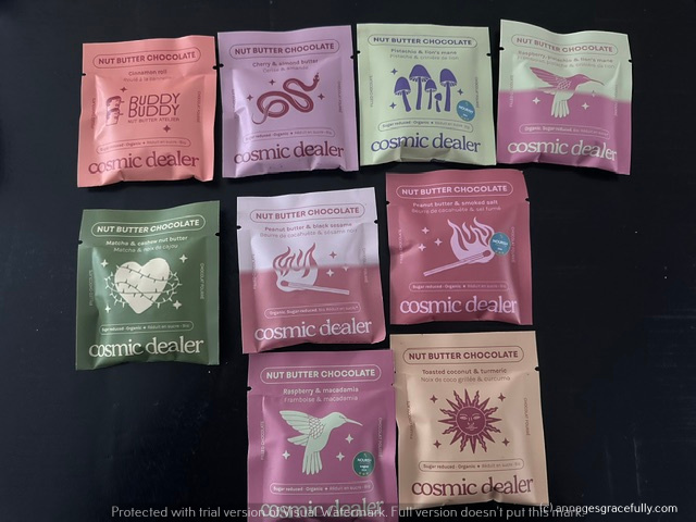 Een assortiment van verpakkingen met 'Nut Butter Chocolate' van Cosmic Dealer, met verschillende smaken en ontwerpen.